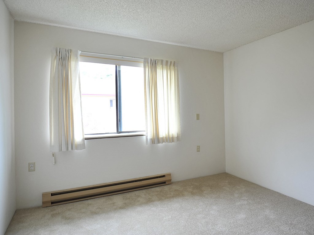 an empty room with a window and curtains
