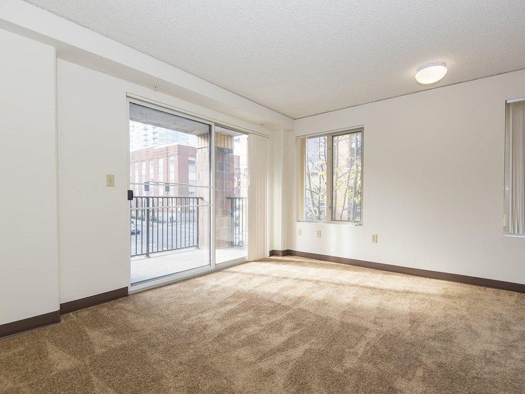an empty living room with a sliding glass door to a balcony
