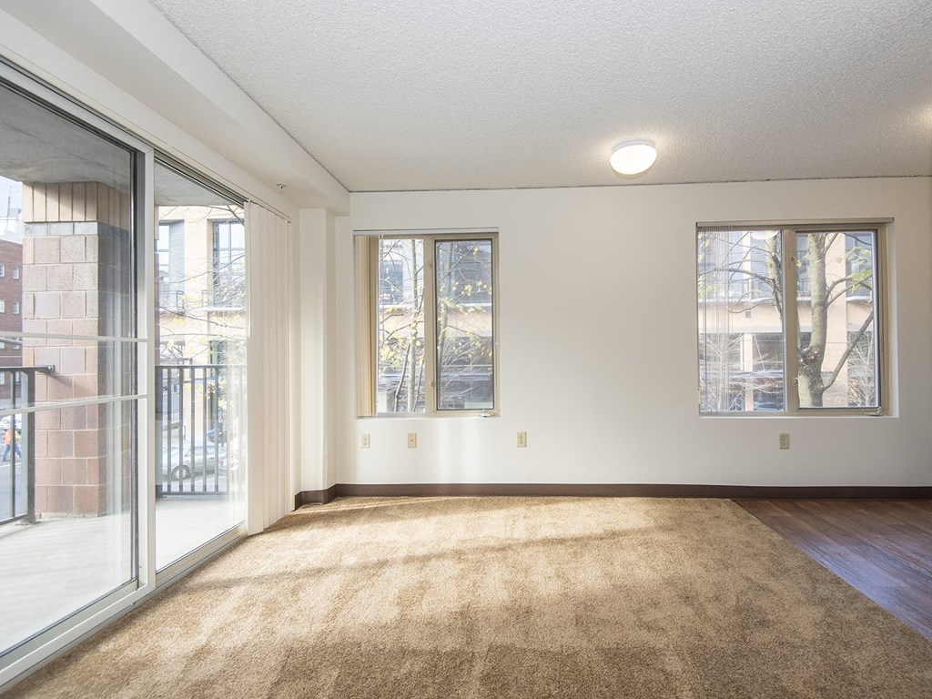 an empty living room with a sliding glass door to a balcony