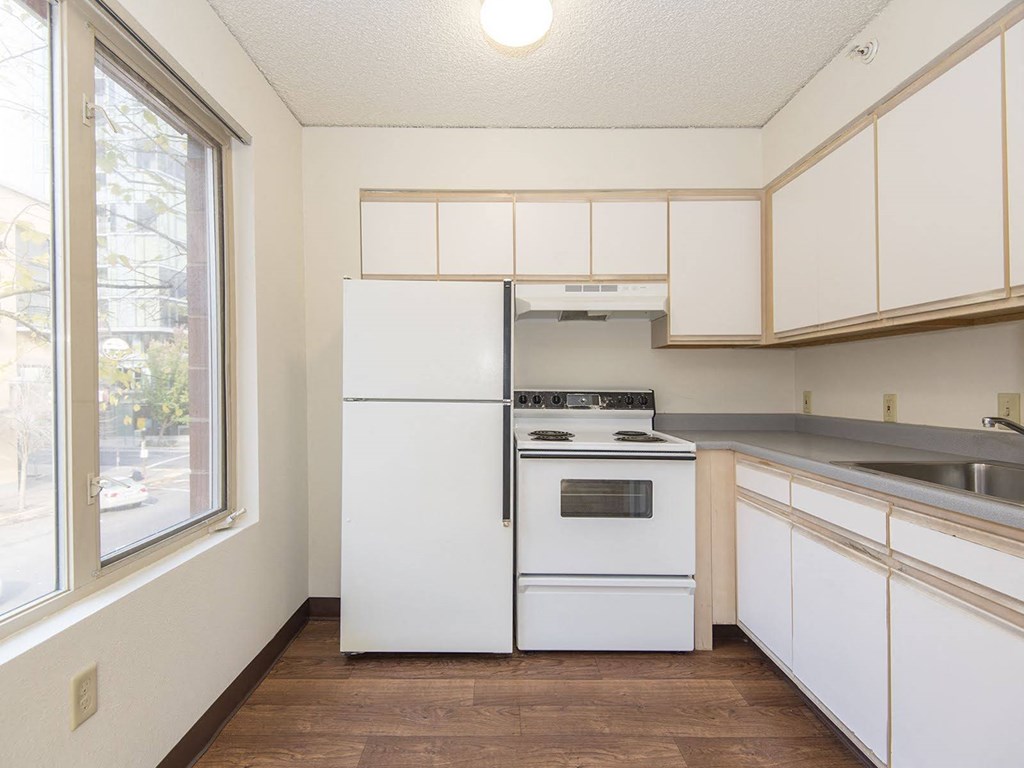 a kitchen with white appliances and a large window