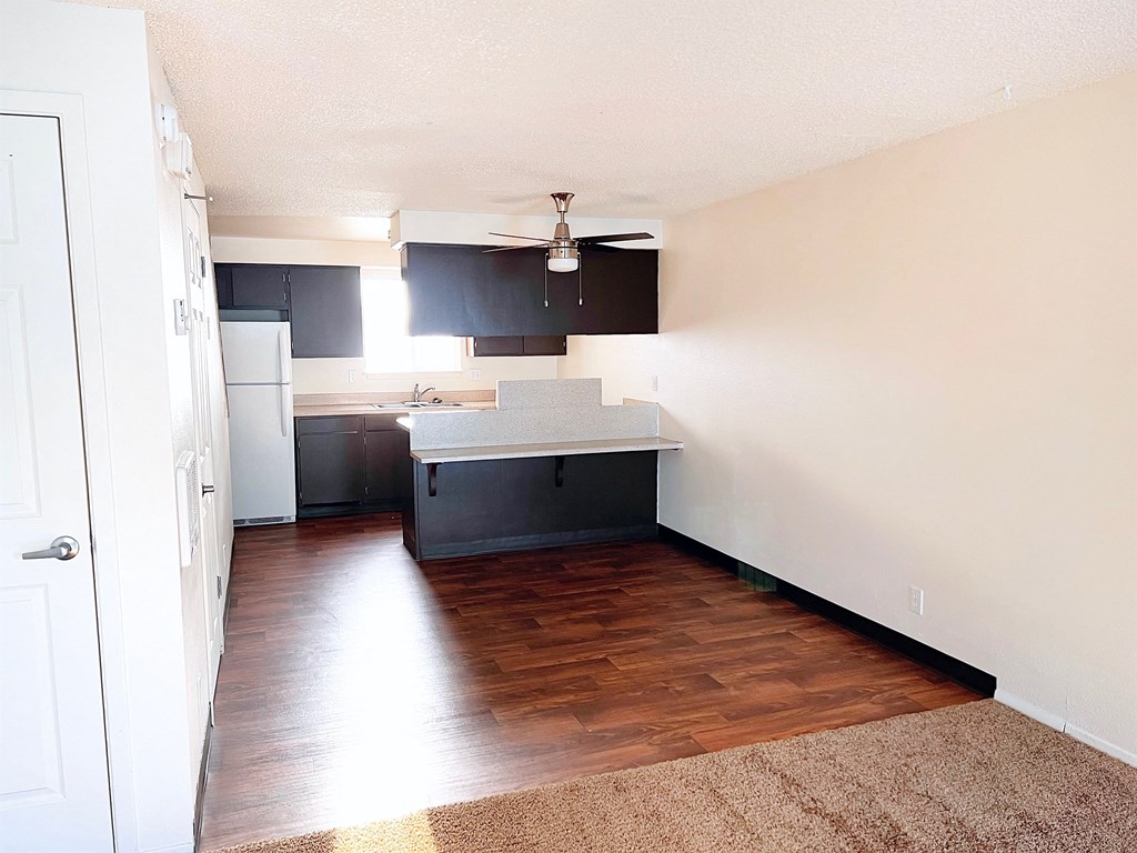 an empty kitchen with wood flooring and black cabinets