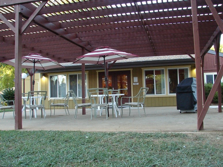 a patio with umbrellas in front of a yellow house