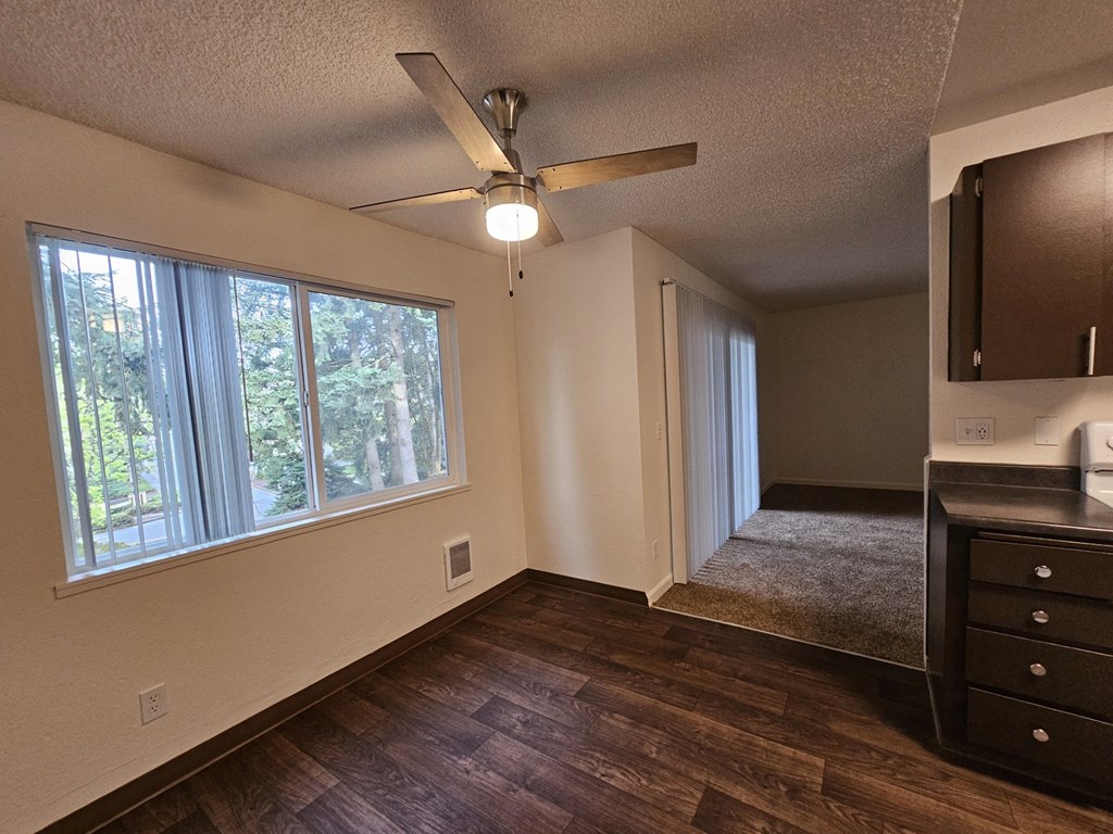 A room with a ceiling fan and a window overlooking trees.