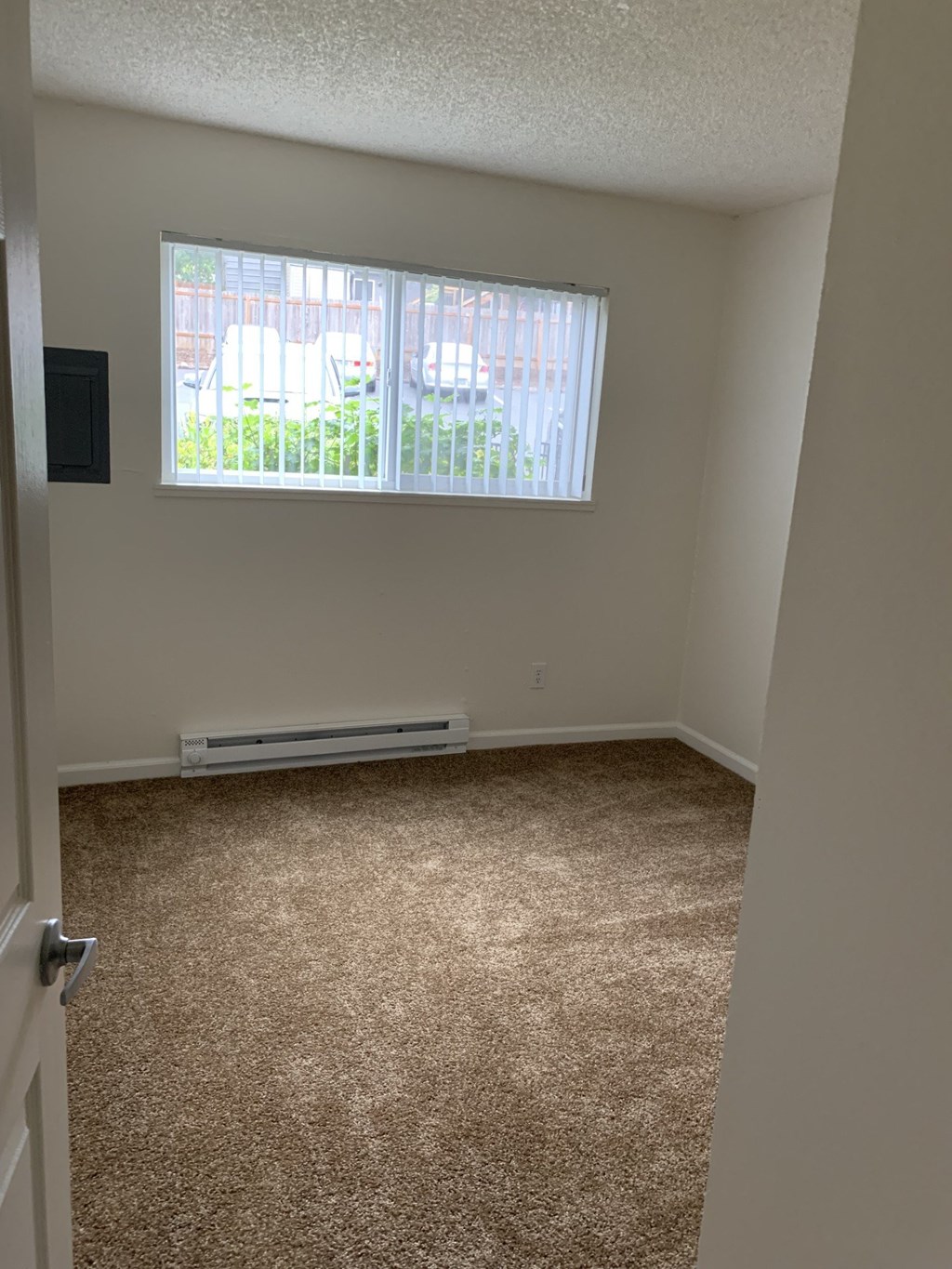 A room with a window and a carpeted floor.