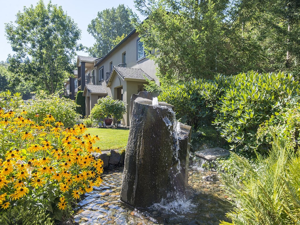 a water fountain in a garden with a house in the background
