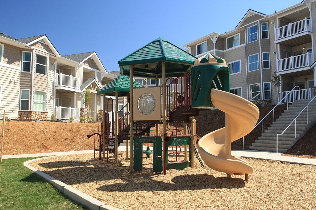 a playground with a slide in front of an apartment building