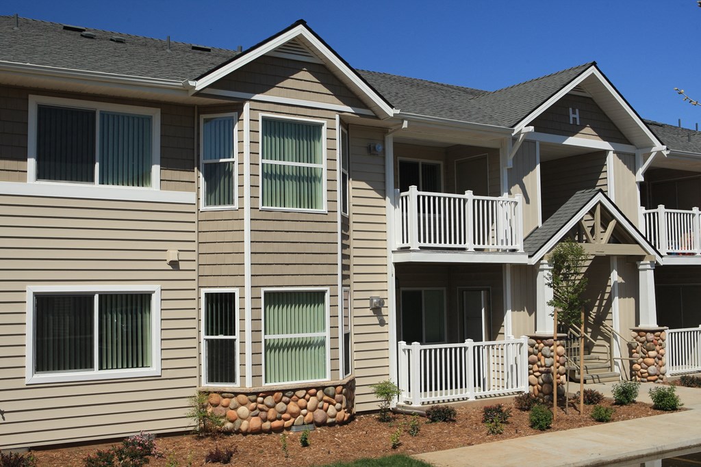 an apartment building with tan siding and a balcony