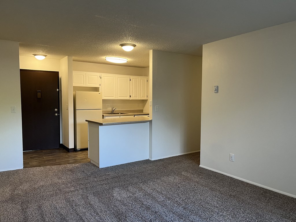 a bedroom with an open door and a kitchen in the background