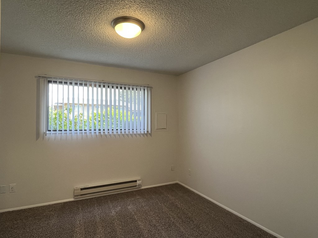 a bedroom with a large window and a carpeted floor