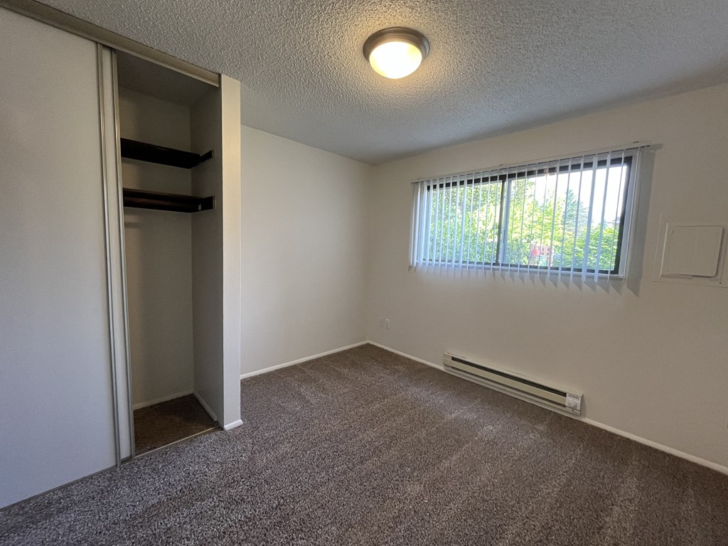 an empty bedroom with a closet and a large window