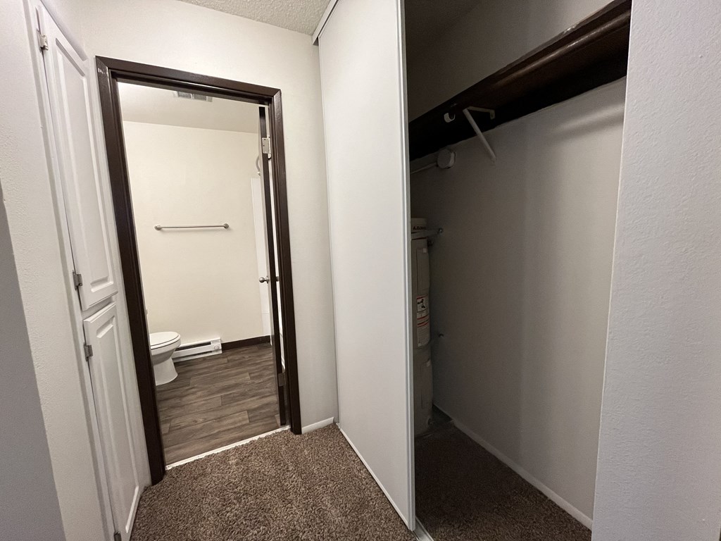 an open door leads to a bathroom with a toilet and a closet