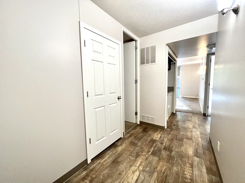 an empty living room and hallway with white doors and a wood floor