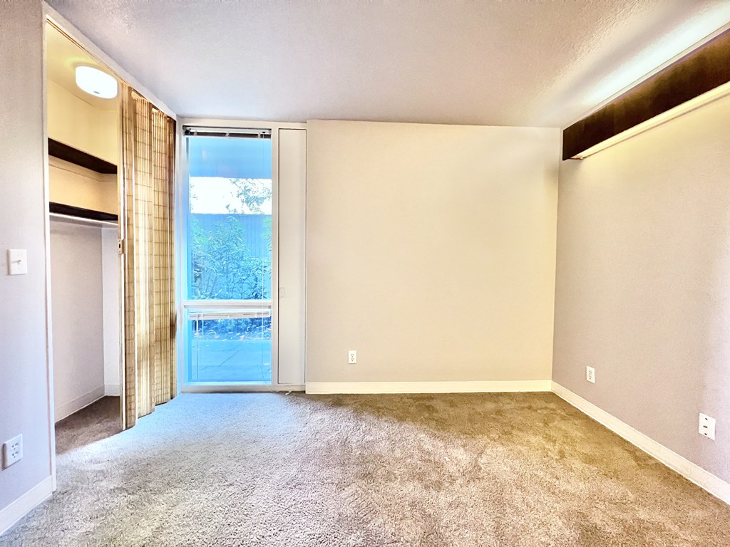 an empty living room with a sliding glass door to a balcony
