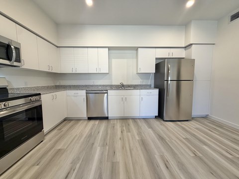 A kitchen with white cabinets and a wooden floor.