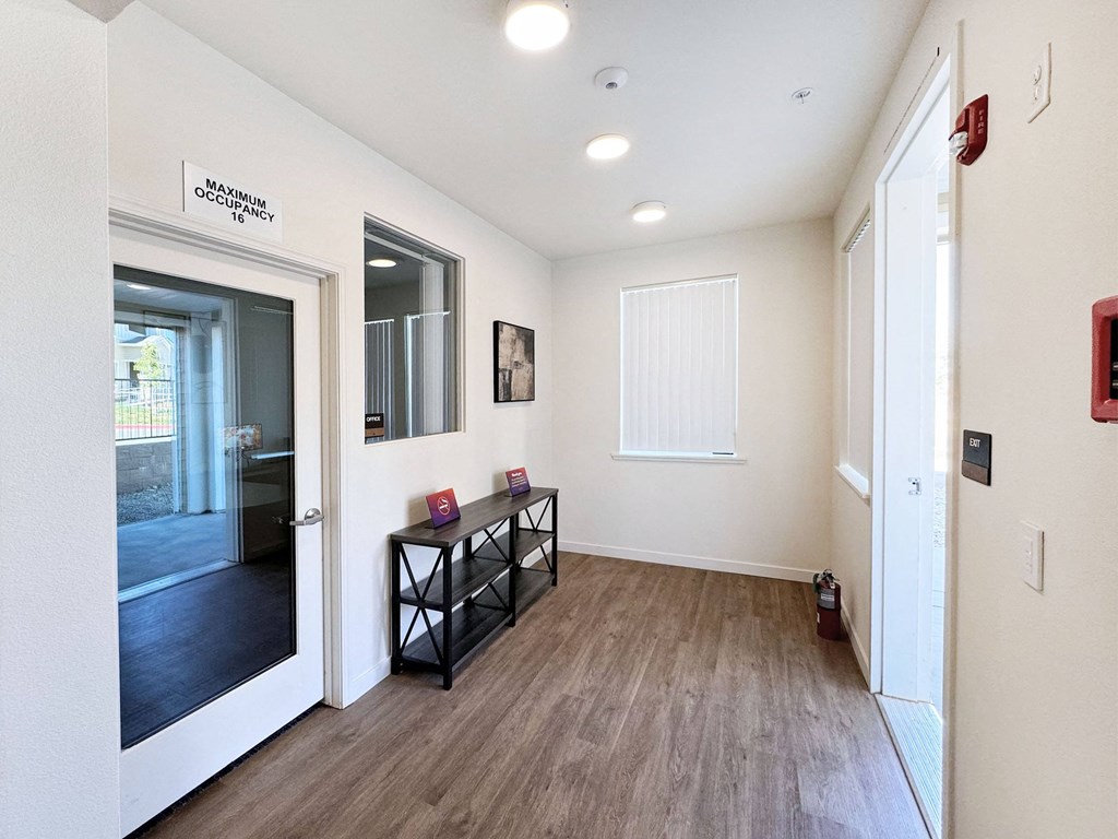 a hallway with a mirror and a door to a room with a wood flooring