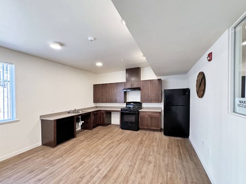 a kitchen and living room with wood flooring and a black refrigerator