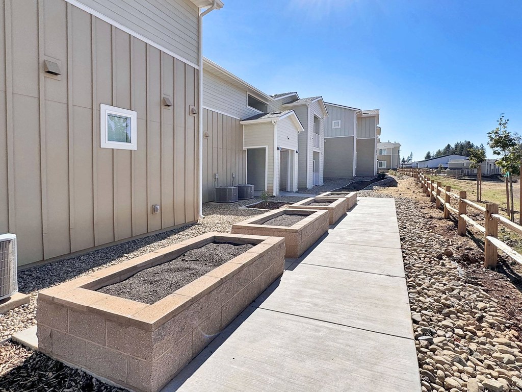 a row of homes with cement planting beds and a sidewalk