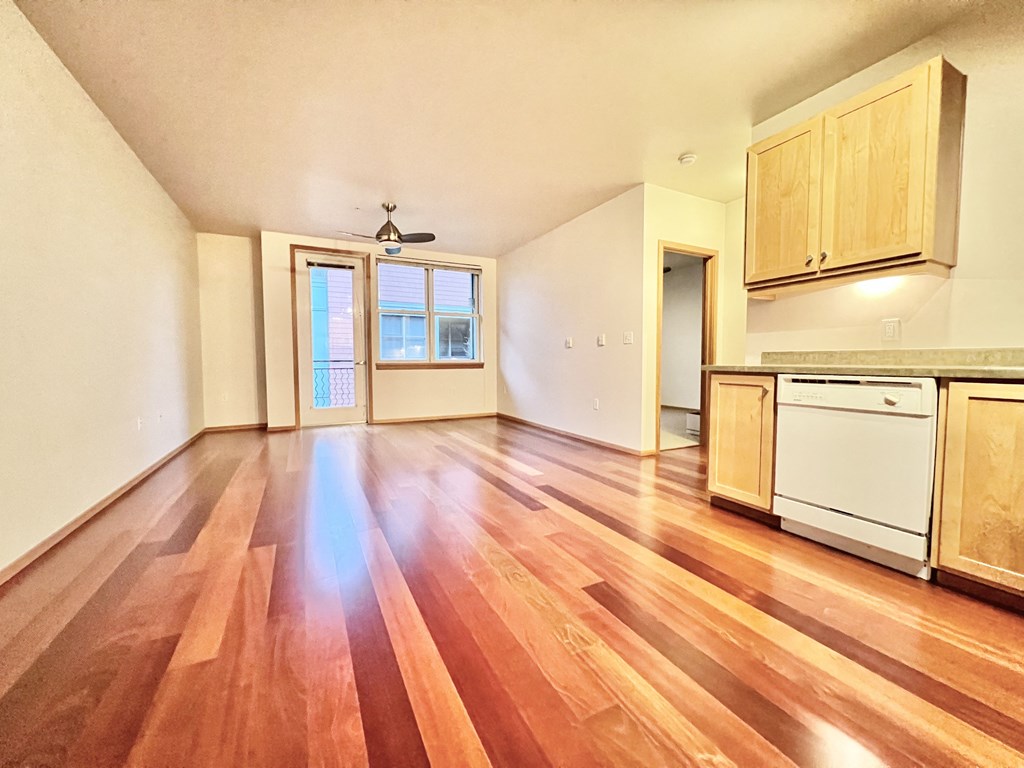 the living room and kitchen of an empty house with wood floors