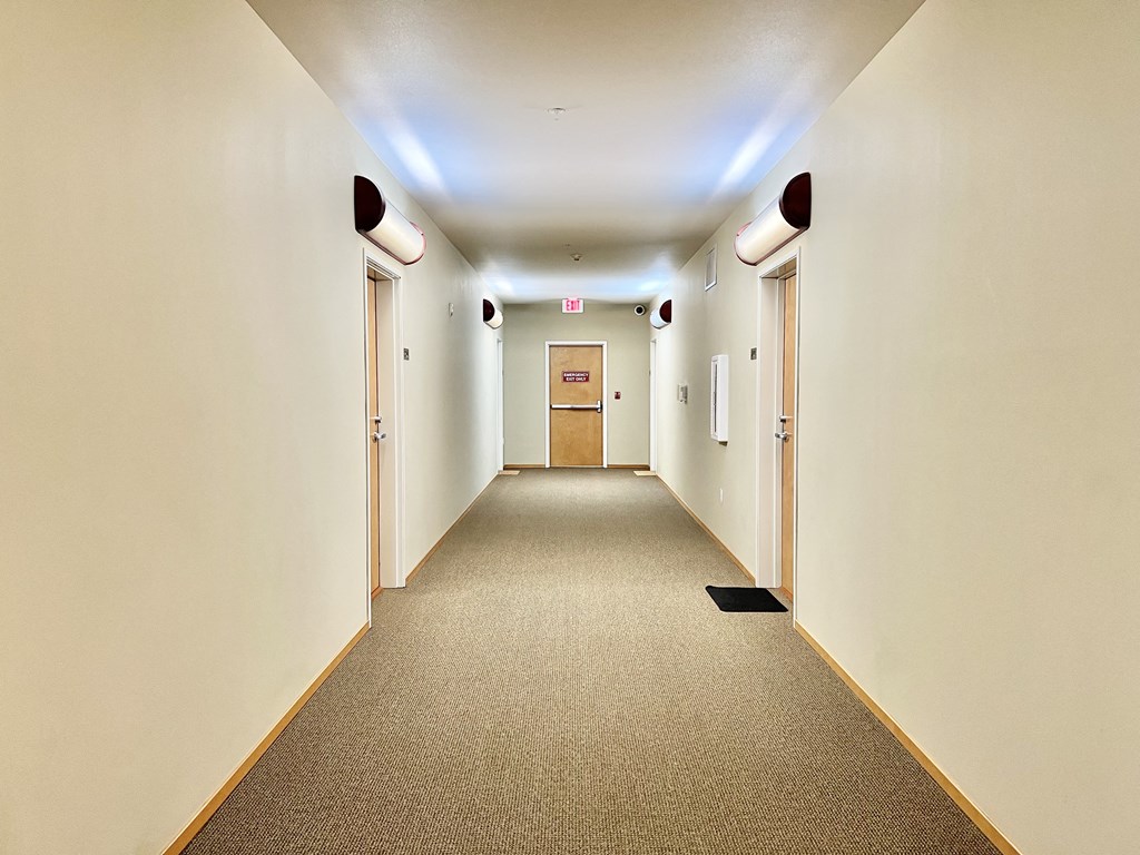 a hallway with a carpeted floor and white walls and doors