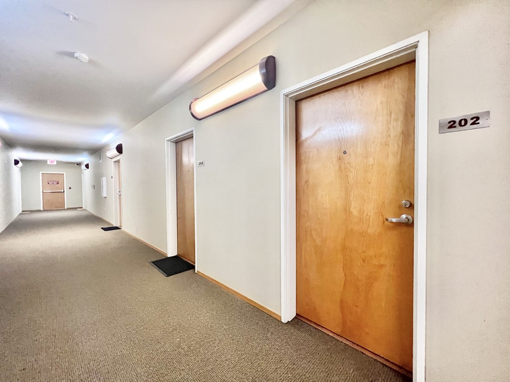 an empty hallway with a wooden door in a building