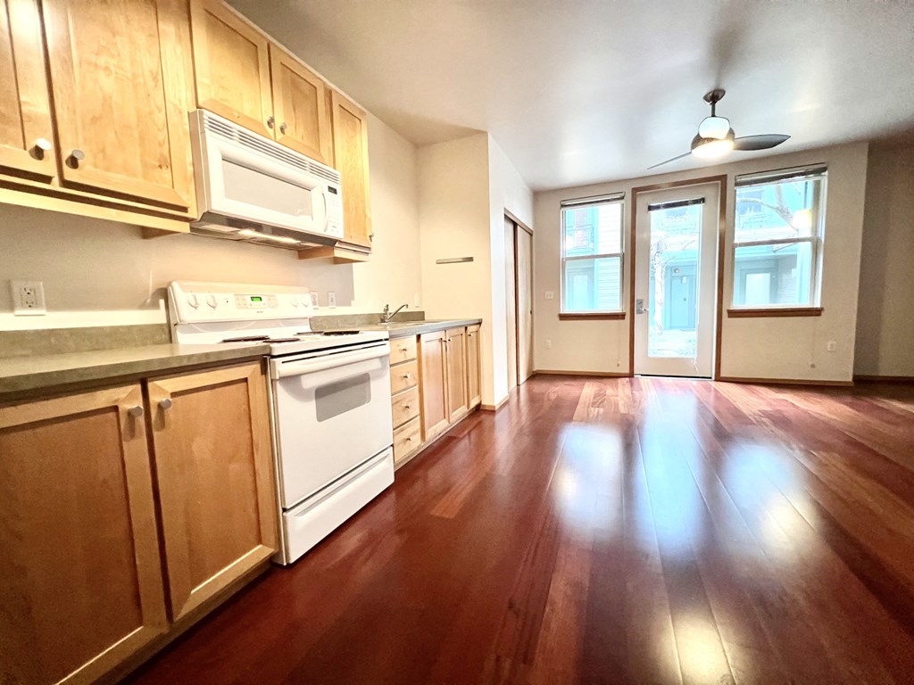 an empty kitchen with wood floors and white appliances