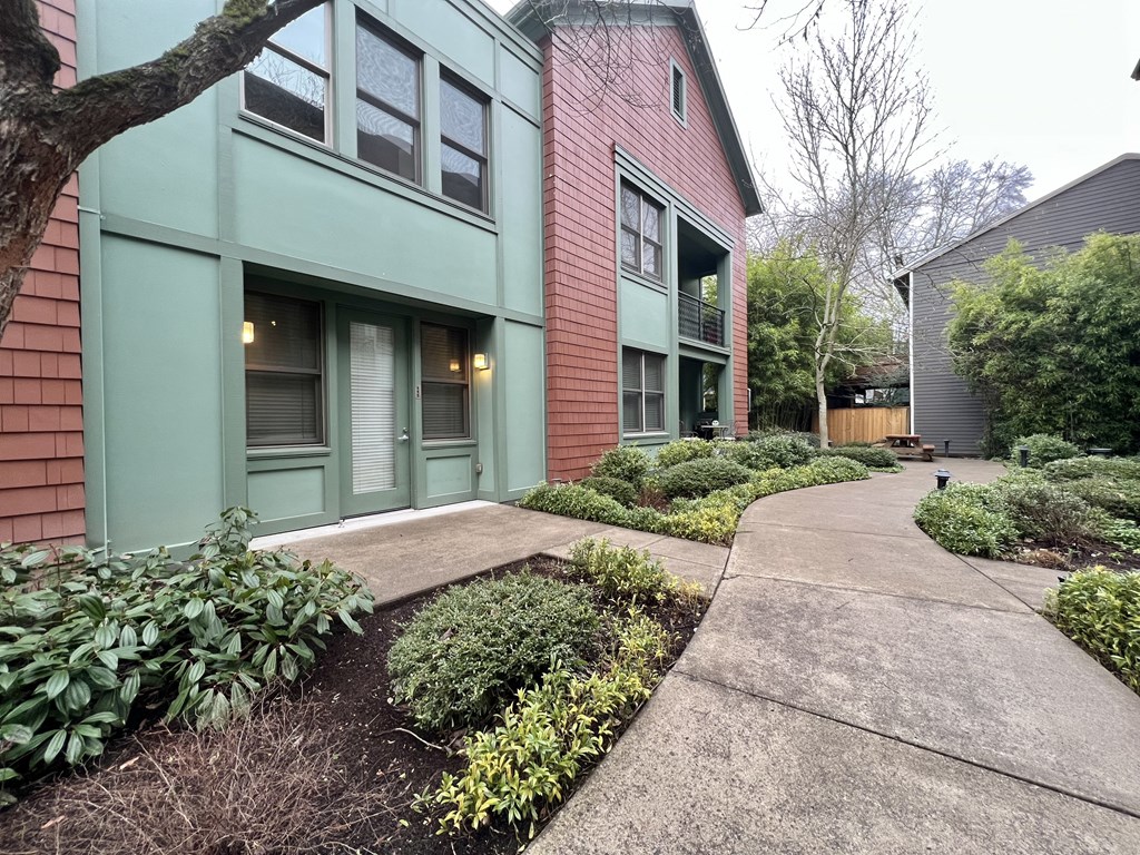a sidewalk in front of a green and red building