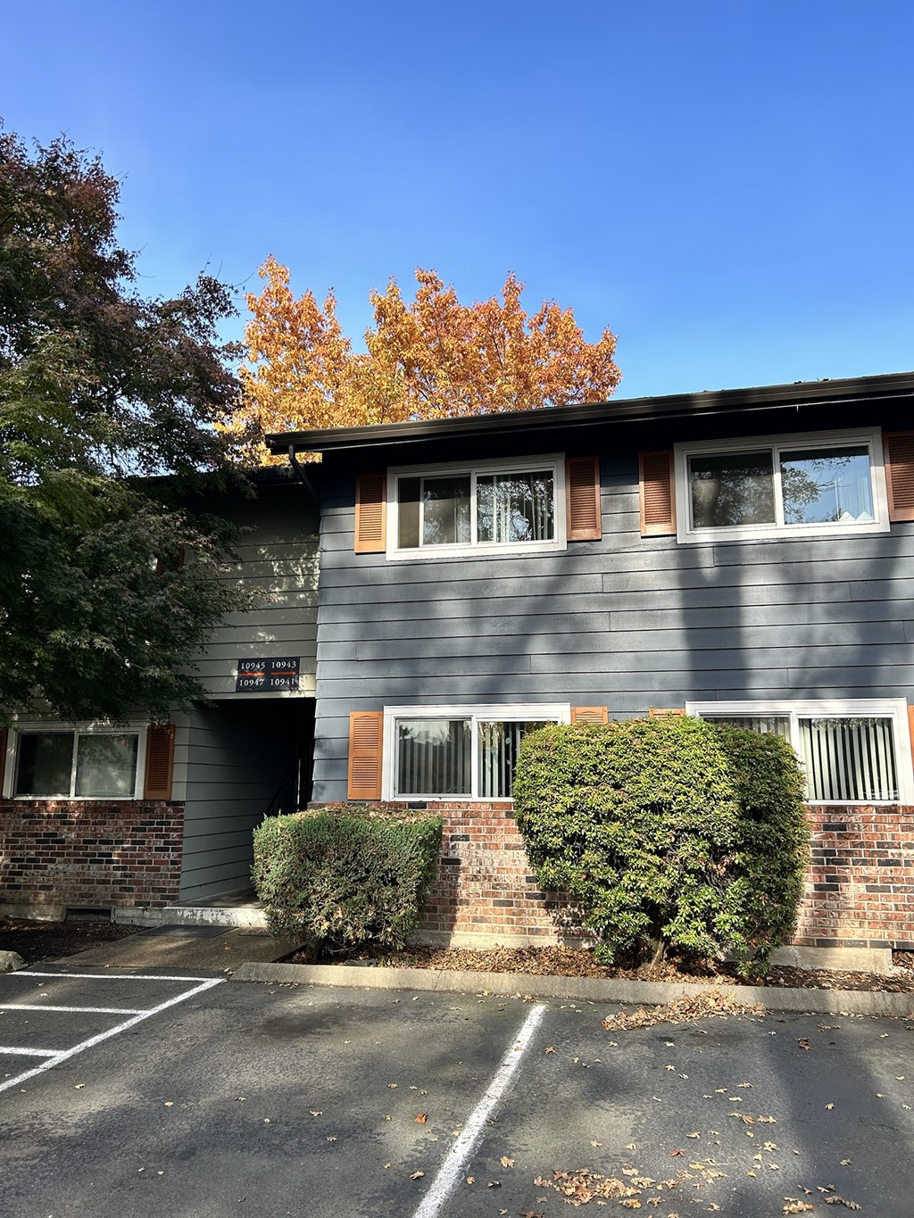A grey building with a parking lot in front.