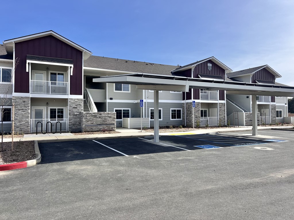 A parking lot in front of a multi-story apartment building.