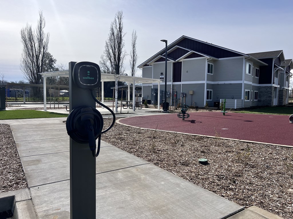 A parking meter is on the left of a sidewalk with a building in the background.