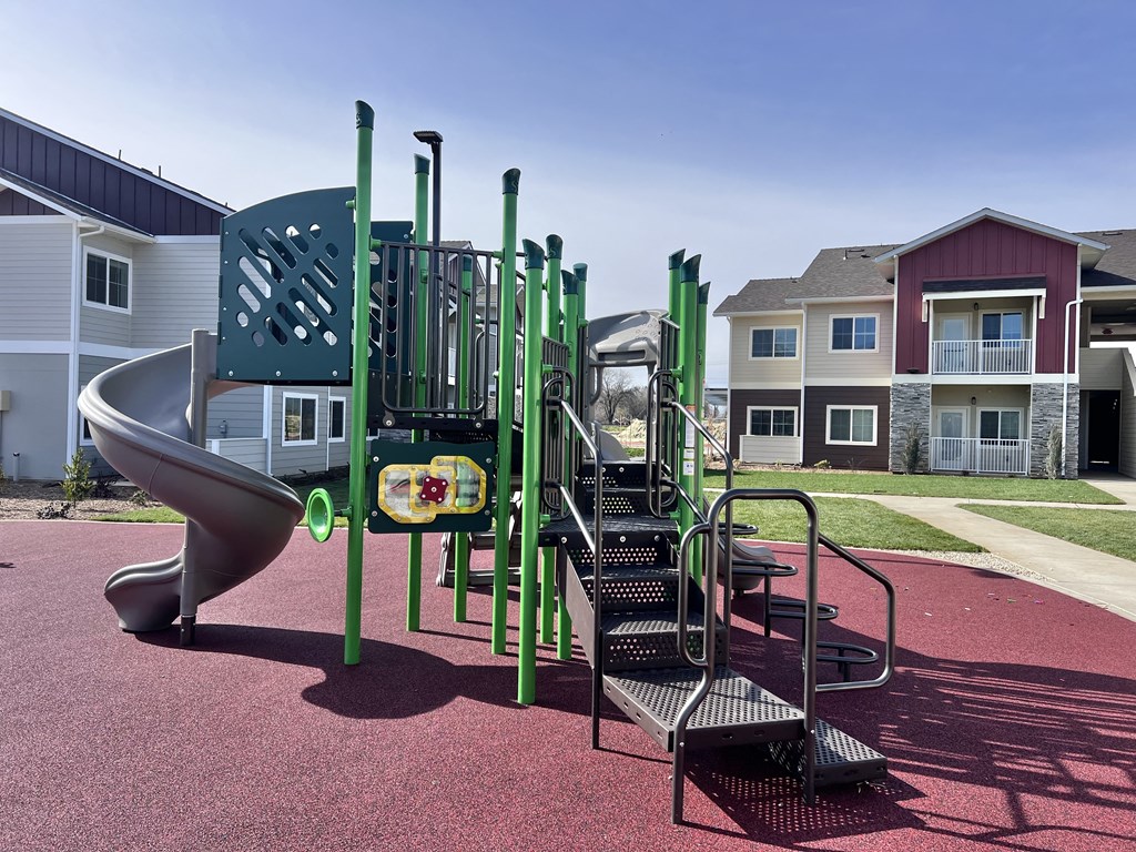 A playground with a green slide and a black and green play structure.