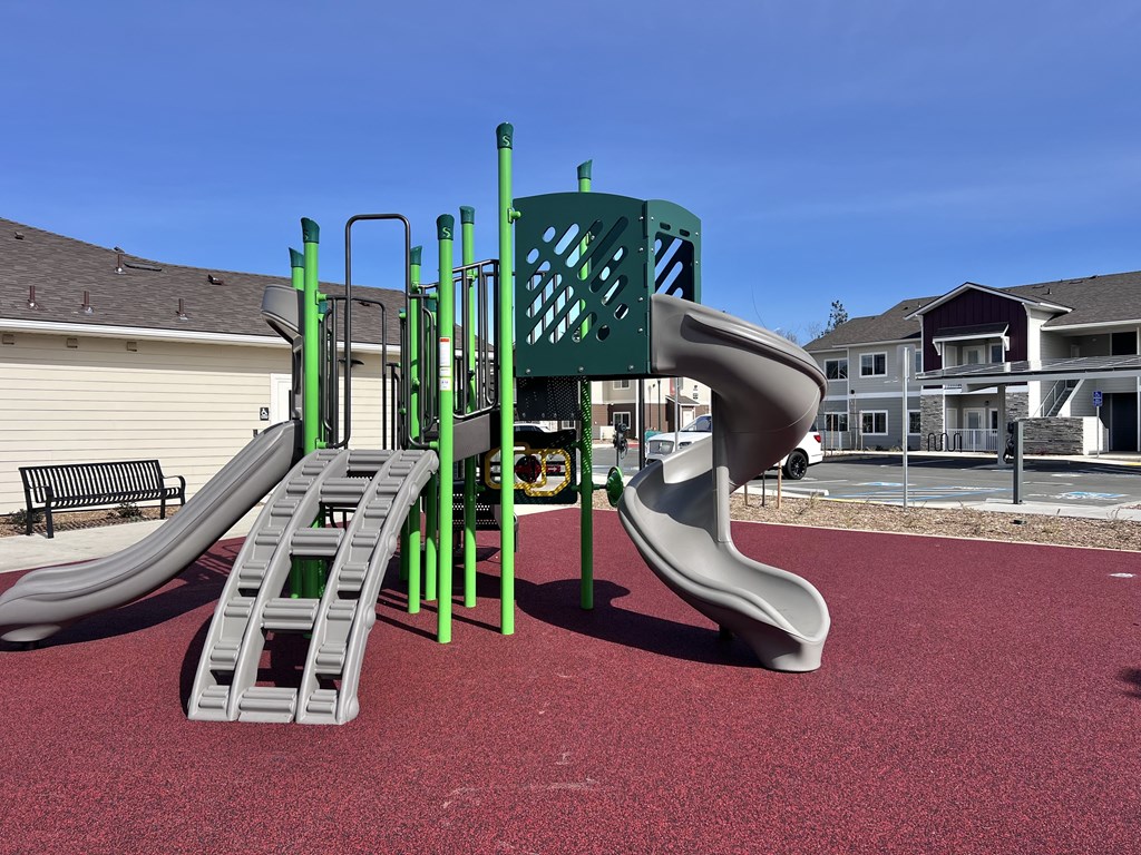 A playground with a green slide and a grey slide.