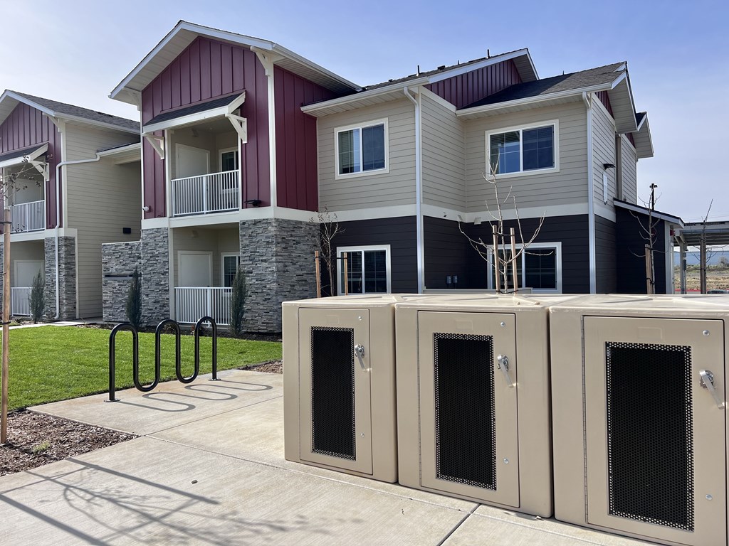 A row of metal vents are in front of apartment buildings.