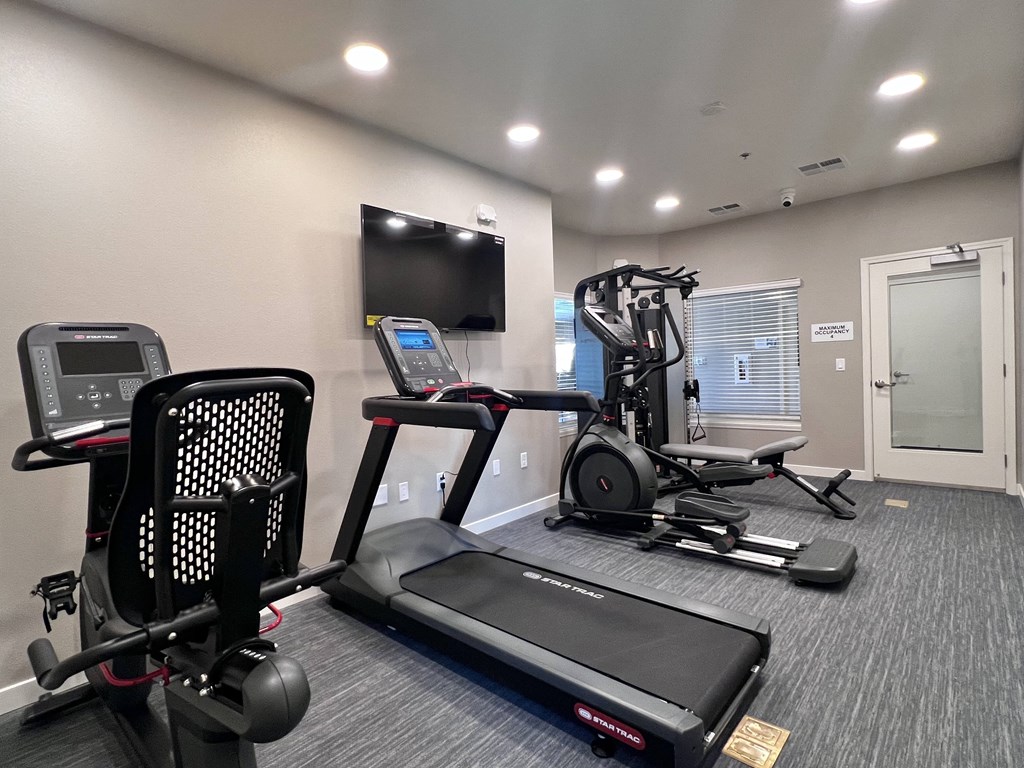 A home gym with a treadmill, elliptical trainer, and a stationary bike.