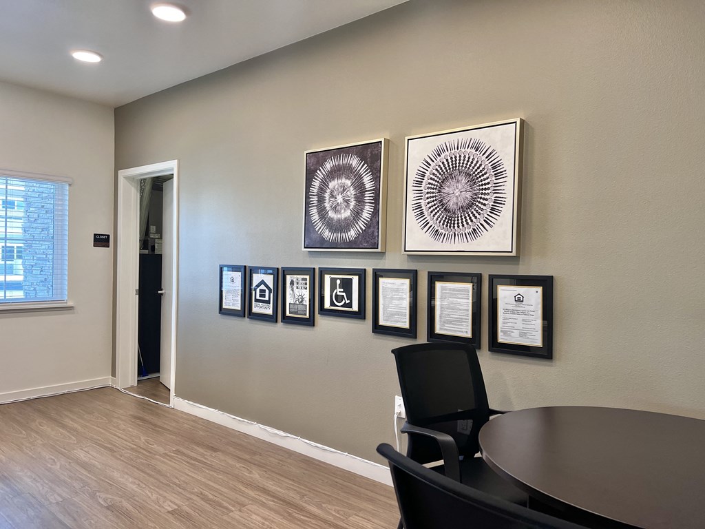 A conference room with a table, chairs and certificates on the wall.