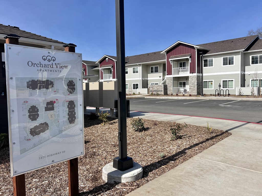 A sign for Orchard View Apartments stands in front of the building.