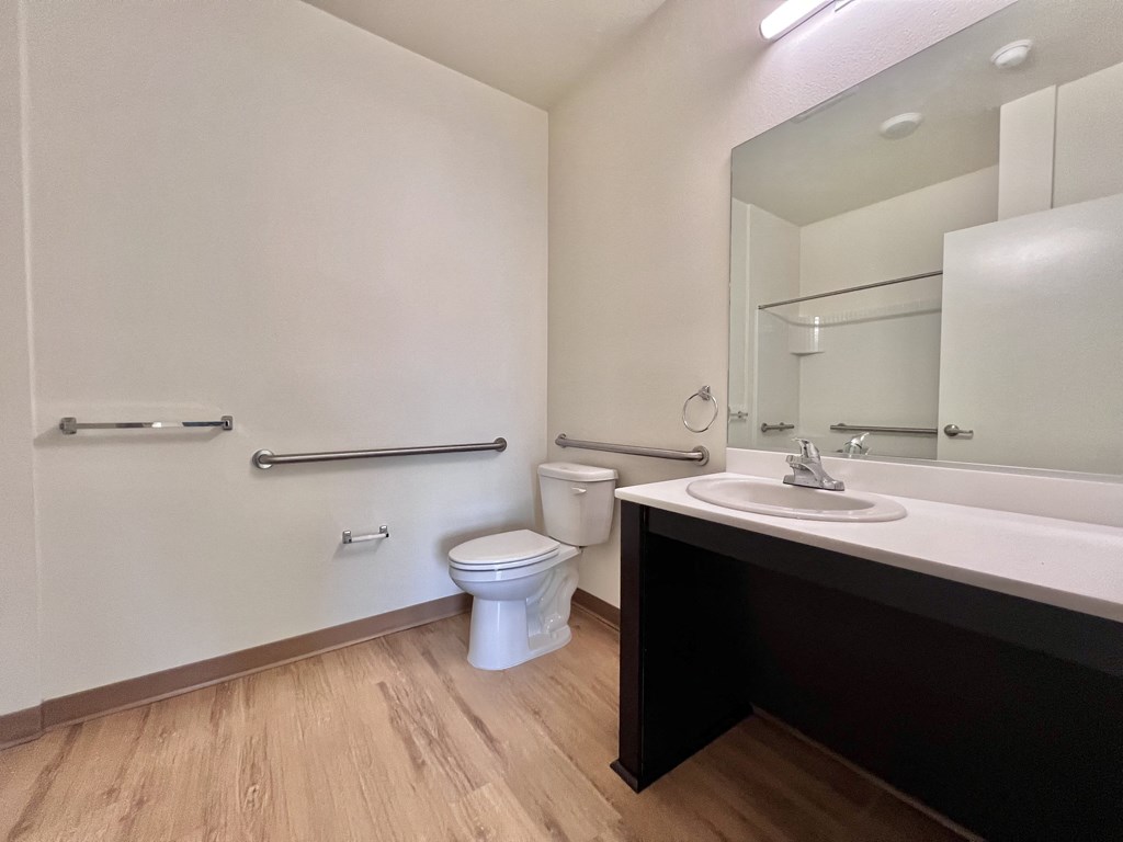 A white toilet sits in a bathroom next to a sink and a bathtub.