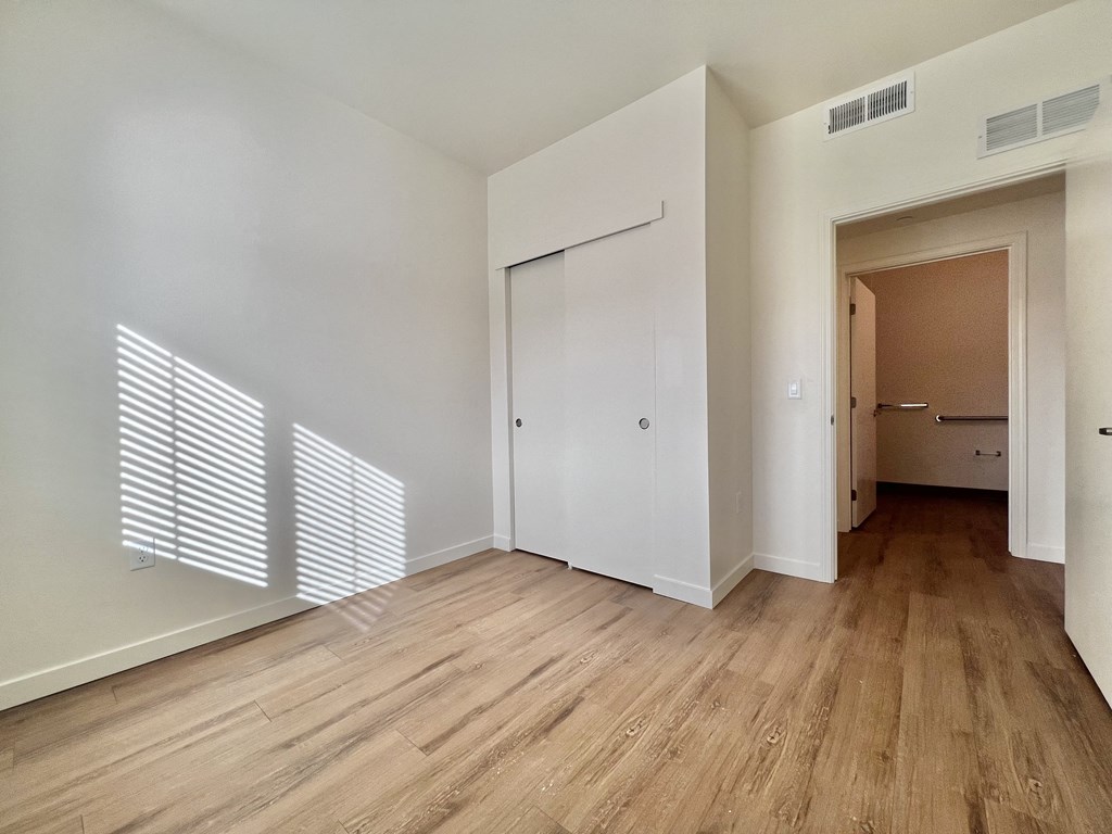 A room with a white door and wooden flooring.