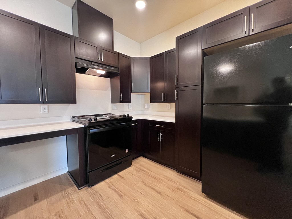 A kitchen with dark wood cabinets and black appliances.