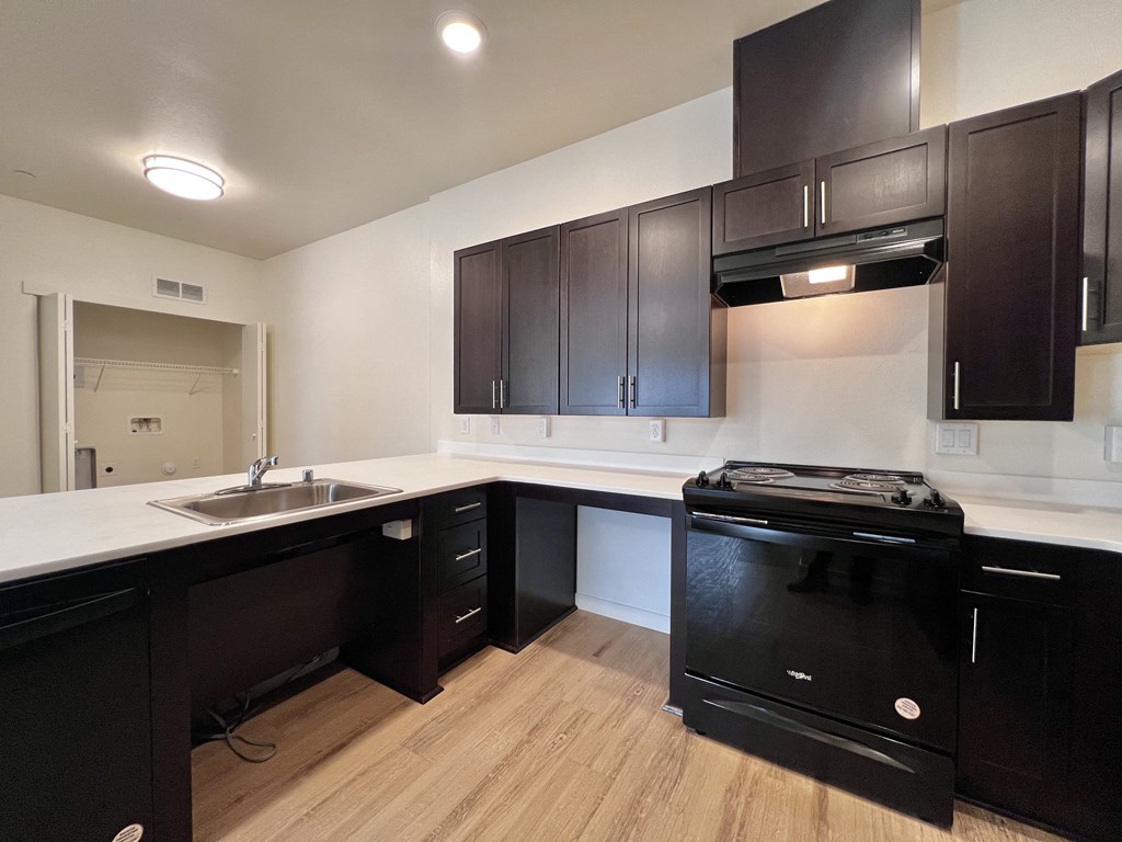 A black oven is in a kitchen with wooden floors and white countertops.