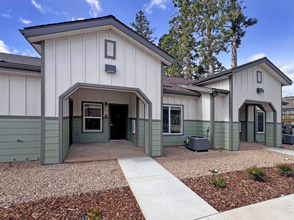 A small building with a white and green exterior and a brown roof.