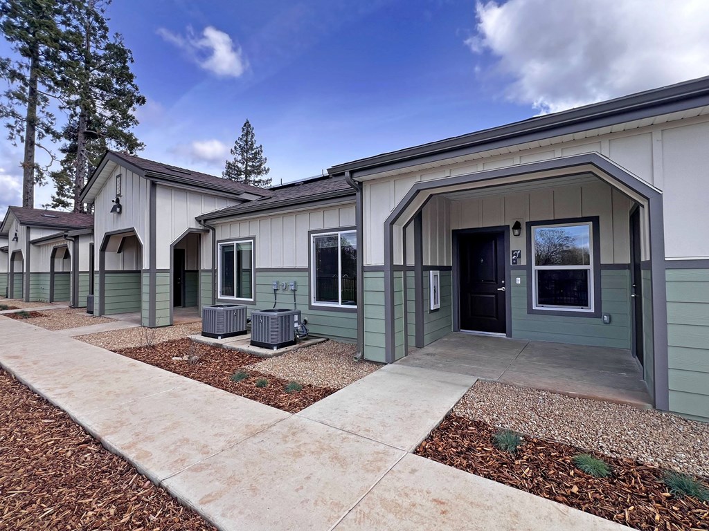 A row of houses with a sidewalk in front.