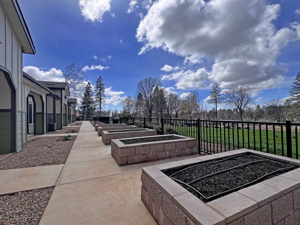 A row of stone planters are lined up on a sidewalk.