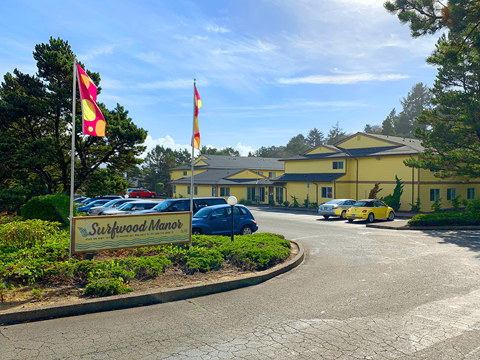 Surfwood Manor sign in front of a building with flags.