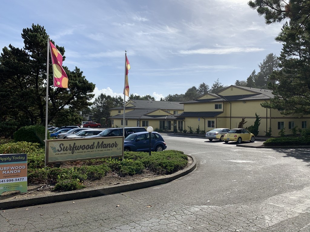a view of the sidewalk market from the street with cars parked in front of it
