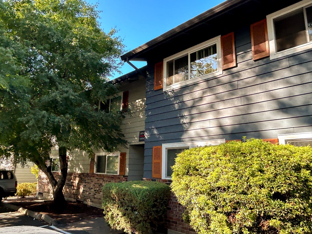 A house with a grey siding and red window trim.