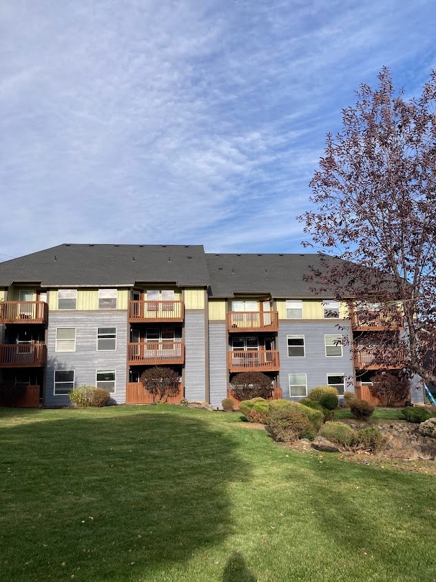 a large apartment building with a green lawn