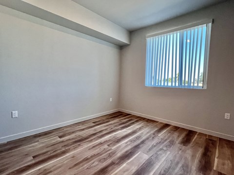 A room with wooden flooring and a window with blinds.