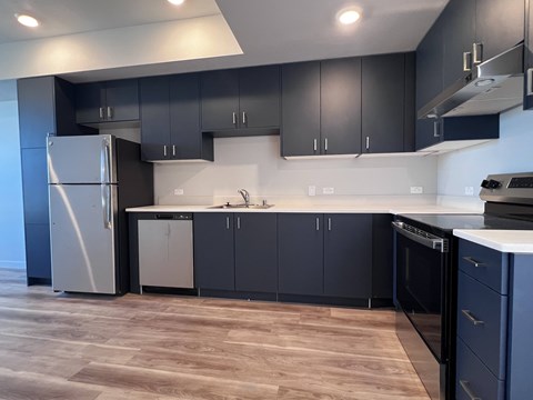 A modern kitchen with dark grey cabinets and a white fridge.