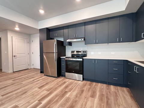 A kitchen with dark blue cabinets and a wooden floor.