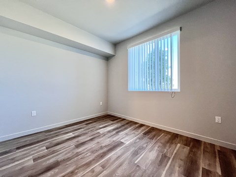 A room with wooden flooring and a window with blinds.